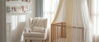 Serene nursery room with cream armchair, wooden crib with sheer canopy, floating shelves, and soft natural light for baby care and interior design projects.