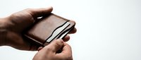 Male hands holding brown leather wallet with credit cards on white background for financial and shopping concepts.