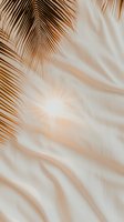 Palm leaves casting soft shadows on light beige fabric background create gentle flowing lines and natural patterns for minimalist tropical design.