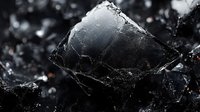 Dark angular crystal formation with jagged edges and reflective surfaces in black and gray tones, showing natural mineral structure and geological patterns in macro photography.