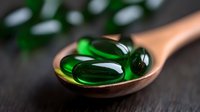 Green translucent soft gel capsules on wooden spoon against dark background, macro photography highlighting pharmaceutical supplements with selective focus.