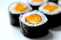 Fresh salmon maki sushi rolls with rice and nori seaweed on white background, shallow depth of field macro photography for restaurant menu design.