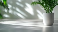 Minimalist white ceramic pot with tropical palm leaves casting natural shadows on light wall background. Trendy interior design element.