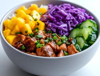 Fresh poke bowl with glazed salmon chunks, diced mango, purple cabbage slaw and cucumber slices arranged in sections, garnished with green onions in gray bowl.