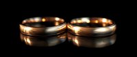 Elegant pair of rose gold wedding bands with brushed matte finish and polished edges on black reflective surface, showcasing fine jewelry craftsmanship and romantic symbolism.