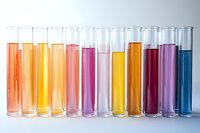 Colorful liquid samples in glass test tubes arranged in row showing gradient of vibrant solutions from orange to blue on white background for scientific research.