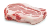 Fresh raw pork chop with marbling and fat cap isolated on white background, ready for cooking or butcher shop display. High quality meat cut.
