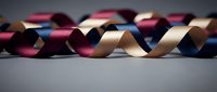 Colorful satin ribbons in burgundy, pink, gold and navy blue creating elegant curved patterns on neutral background for crafting and decoration projects.