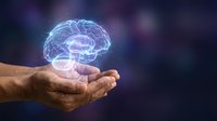 Glowing digital brain hologram floating above cupped hands against dark purple background representing artificial intelligence and neuroscience concepts.