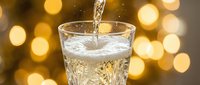 Water pouring into glass with sparkling bokeh background, refreshing beverage concept for hydration, wellness and drink advertising.