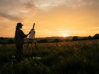 Artist painting landscape at golden hour in rural field with easel and canvas during sunset, capturing nature scenery outdoors.
