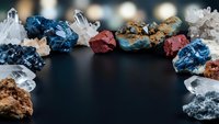 Collection of colorful mineral specimens and crystals arranged in circular frame on dark surface for geology education and gemstone display.