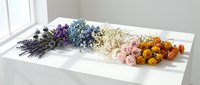 Colorful dried flower arrangement with lavender, roses, and seasonal blooms displayed on white wooden surface for crafting and home decoration projects.