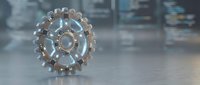 Futuristic transparent glass gear wheel with metallic elements on reflective surface in modern industrial setting for technology and engineering concepts.