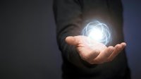 Businessman holding glowing energy orb in palm showcasing innovation technology and future business solutions in corporate environment.