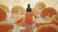 Fresh orange serum dropper bottle among juicy citrus slices with water drops and soft natural lighting, cosmetic skincare product photography.
