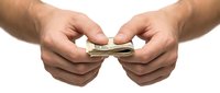 Male hands holding and tearing paper currency in half against white background, representing financial loss, bankruptcy, or money problems.
