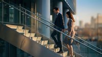Professional business couple walking up modern office stairs during golden hour with city skyline backdrop for corporate success concepts.