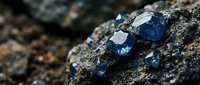 Raw blue sapphire crystals embedded in natural rock formation showcasing precious gemstone mining and geological treasure discovery.