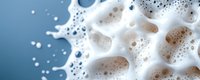 White soap foam bubbles and suds macro close-up on blue background. Clean fresh washing detergent texture with copy space for text.