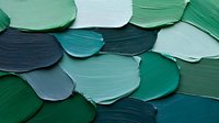 Abstract green paint swatches in various shades create textured brushstroke pattern. Thick acrylic strokes form organic shapes against dark background. Artistic palette sampling.