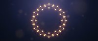 Warm glowing string lights arranged in circular frame on dark blue background with bokeh effect, suitable for holiday decorations, festive designs, and seasonal marketing materials.