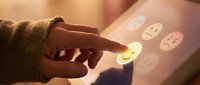 Child's hand touching glowing emoji faces on interactive digital screen, exploring emotions and user interface design for educational apps and touchscreen technology.