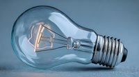 Glowing filament light bulb on blue background, symbolizing innovation, creativity, and energy efficiency for business and technology concepts.