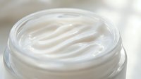 Luxurious white moisturizing cream with smooth swirled texture in open glass jar for skincare and beauty routine applications.