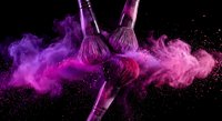 Professional makeup brushes creating explosive purple and pink powder clouds against black background for cosmetic advertising and beauty campaigns.