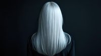 Young woman with long straight platinum blonde hair viewed from behind against dark background for beauty and fashion concepts.