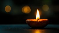 Traditional clay oil lamp with burning flame against dark background with bokeh lights creating spiritual and peaceful ambiance for meditation and diwali celebration.