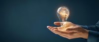 Businessman holding glowing light bulb with brain inside against dark blue background, representing innovation, creativity, and intelligent business solutions.