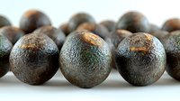 Fresh whole black peppercorns in macro view showing natural texture and pattern of dried spice balls against white background, food photography.