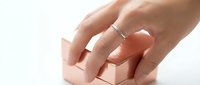 Woman hand with wedding ring gently touching wooden building blocks on white background. Concept of construction, planning, foundation building.