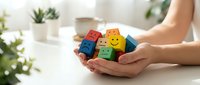 Hands holding colorful wooden blocks with emoji faces showing different emotions for mental health awareness and emotional wellbeing concepts.