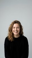 Happy young Caucasian woman with curly blonde hair laughing in black knit sweater against neutral background for lifestyle and portrait concepts.