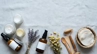 Natural organic skincare products with dried flowers and wooden tools arranged on marble surface for spa wellness and beauty routines.