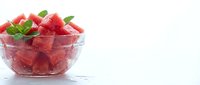 Fresh watermelon cubes in glass bowl with mint leaves, isolated on white background for food and beverage design projects.