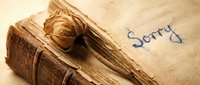 Aged vintage book with dried rose and handwritten sorry note on worn paper, evoking regret, apology, and nostalgic emotion.