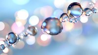 Transparent water droplets in a row with colorful bokeh background creating dreamy, ethereal atmosphere for cosmetic or wellness advertising.
