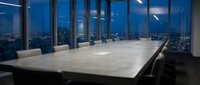 Modern conference room with large marble table and panoramic city skyline view through floor-to-ceiling windows at dusk for corporate meetings.