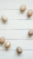 Natural brown eggs scattered on white wooden planks background for organic farm fresh food concepts and healthy cooking designs.
