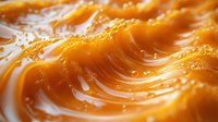 Swirling golden caramel sauce with smooth waves and bubbles in macro photography, showing rich texture and glossy surface for dessert and confectionery designs.