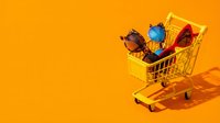Miniature shopping cart filled with colorful gemstones and jewelry on bright yellow background. Retail and e-commerce concept for online shopping, luxury goods sales, and consumer purchasing.