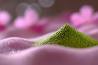 Green matcha tea powder pile on pink surface with soft bokeh background for wellness and culinary applications.