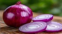 Fresh red onion whole and sliced rings on wooden cutting board against blurred green background, macro food photography for cooking and recipe blogs.