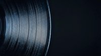 Close-up of vinyl record with detailed grooves and texture on dark background for music and audio production concepts.