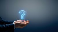 Businessman hand holding glowing blue question mark symbol against dark background, representing inquiry, support, help, and customer service solutions.