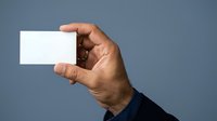 Man holding blank white business card in hand against blue background, suitable for corporate branding and marketing materials.